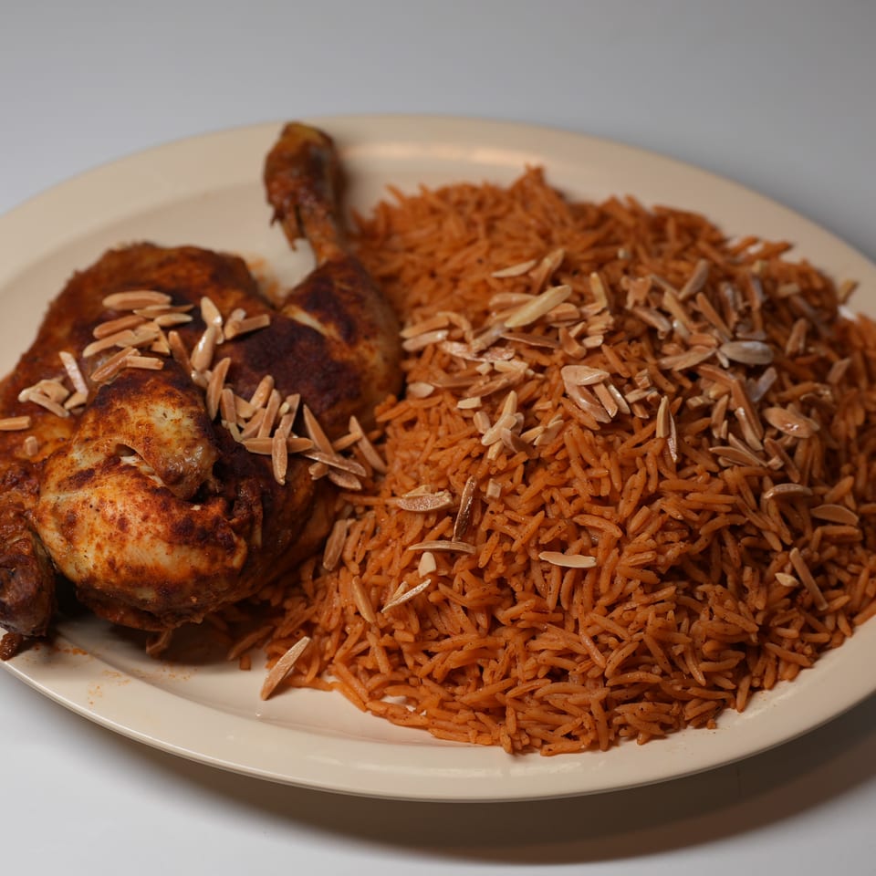 A whole roasted chicken seasoned with spices and topped with slivered almonds, served with rice.