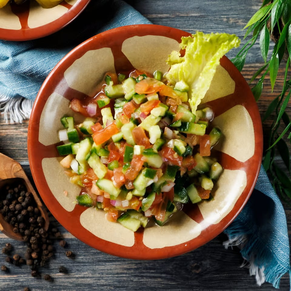A vibrant middle-eastern salad with diced cucumbers, tomatoes, and onions in a rustic bowl.